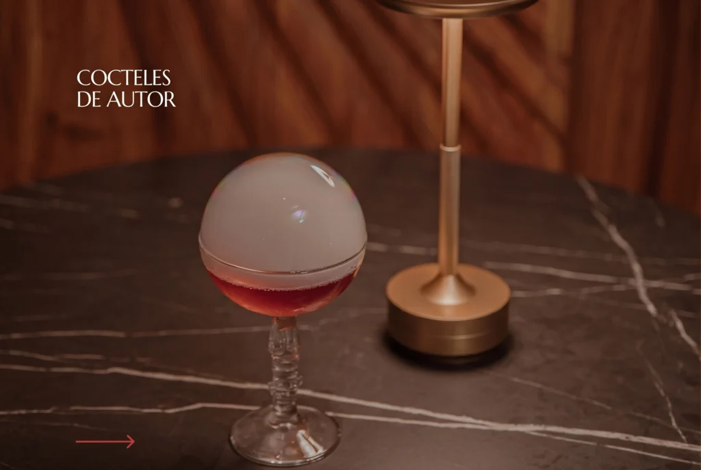 Cóctel de autor con esfera de hielo ahumada en copa de cristal sobre mesa de mármol en ETRO Rooftop, BINN Hotel Medellín