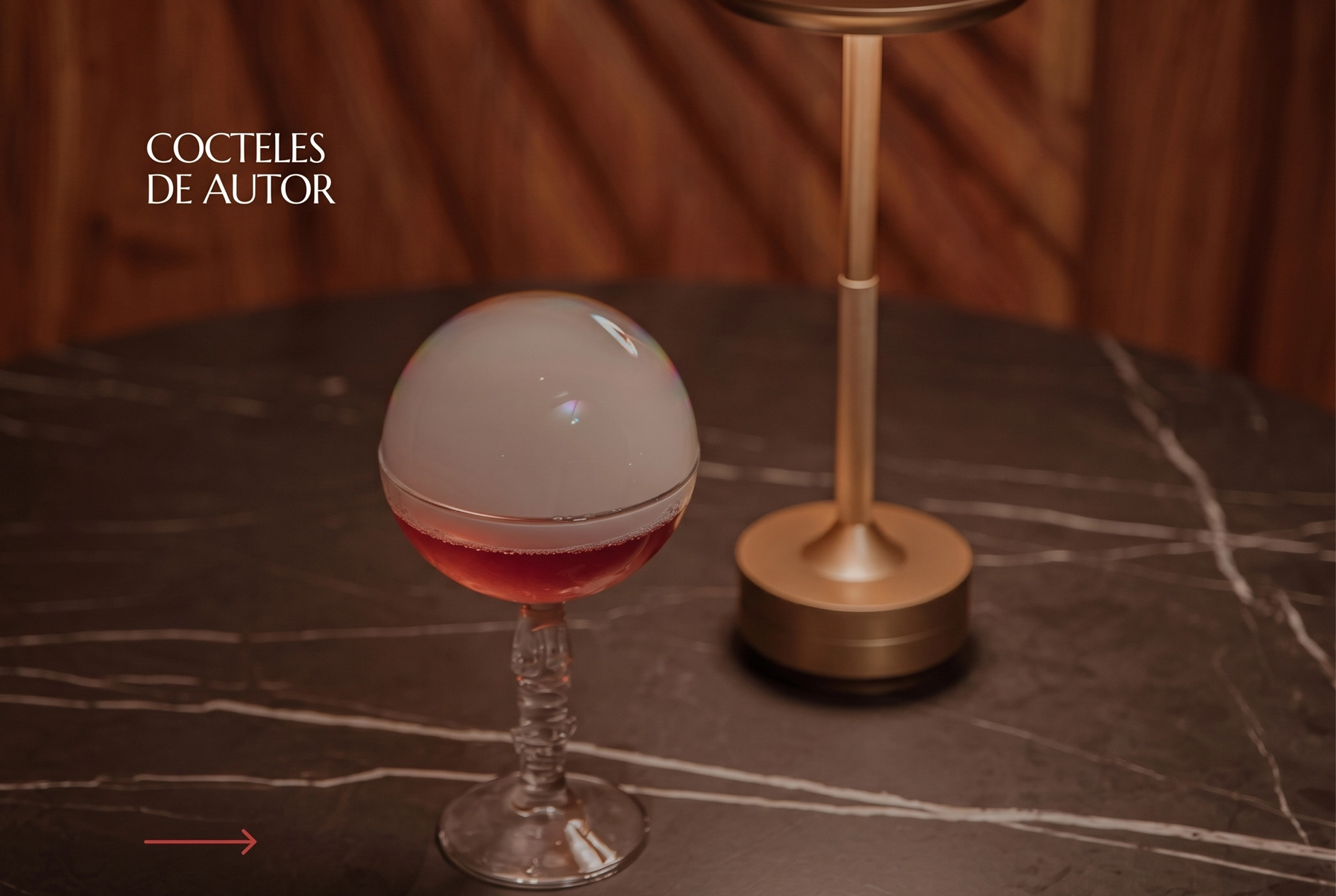 Cóctel de autor con esfera de hielo ahumada en copa de cristal sobre mesa de mármol en ETRO Rooftop, BINN Hotel Medellín