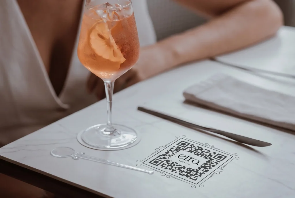 Cóctel spritz con durazno y menú QR de ETRO Rooftop en mesa de mármol, guía para novatos en BINN Hotel Medellín.

