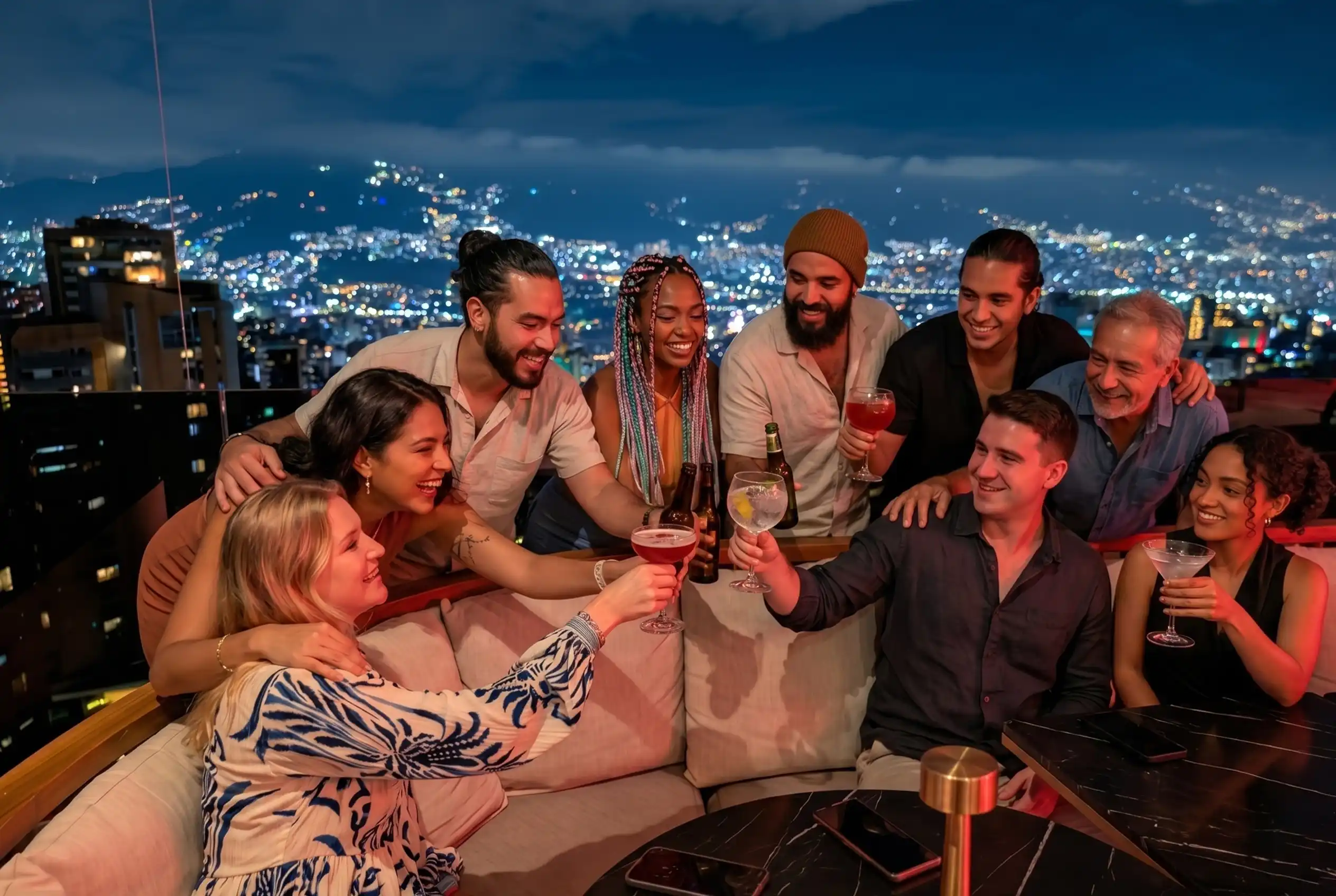 Grupo brindando con cócteles en ETRO Rooftop de BINN Hotel con vista nocturna a Medellín en puente de mayo.