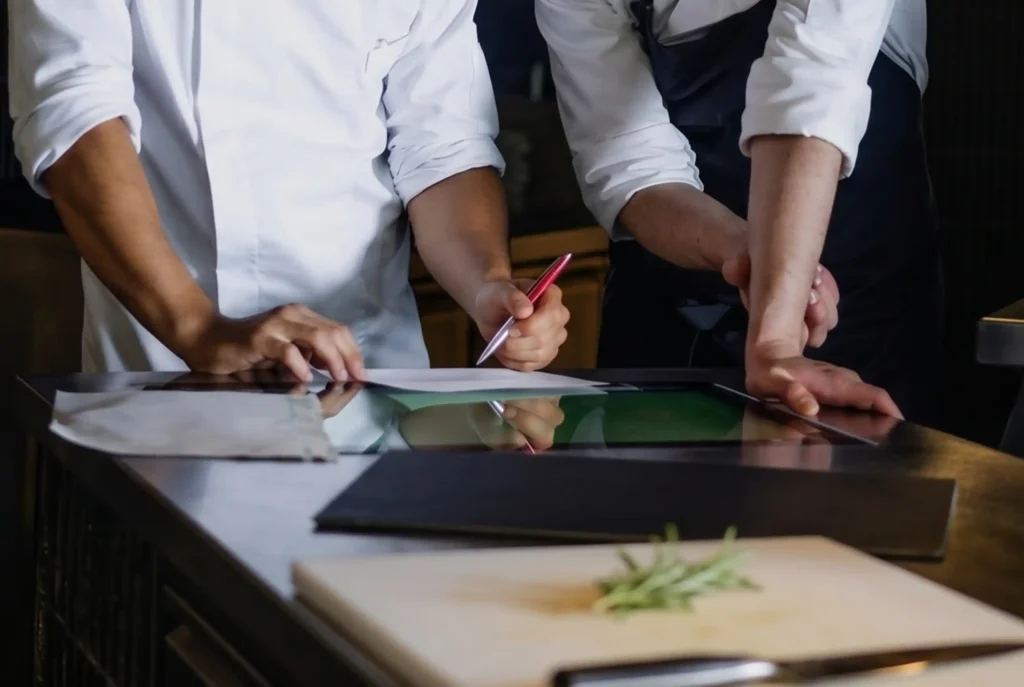 Planificación y gestión de restaurante de autor en La Makha: chefs revisando costos y recetas digitales.