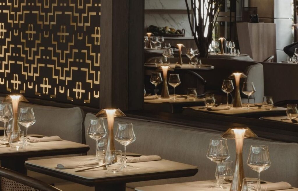 Mesas elegantemente servidas con copas de cristal y lámparas de diseño en el salón principal de La Makha.