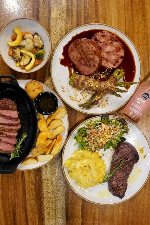 Variedad de cortes de carne y guarniciones artesanales que representan el terroir antioqueño gastronomía en mesa de madera.
