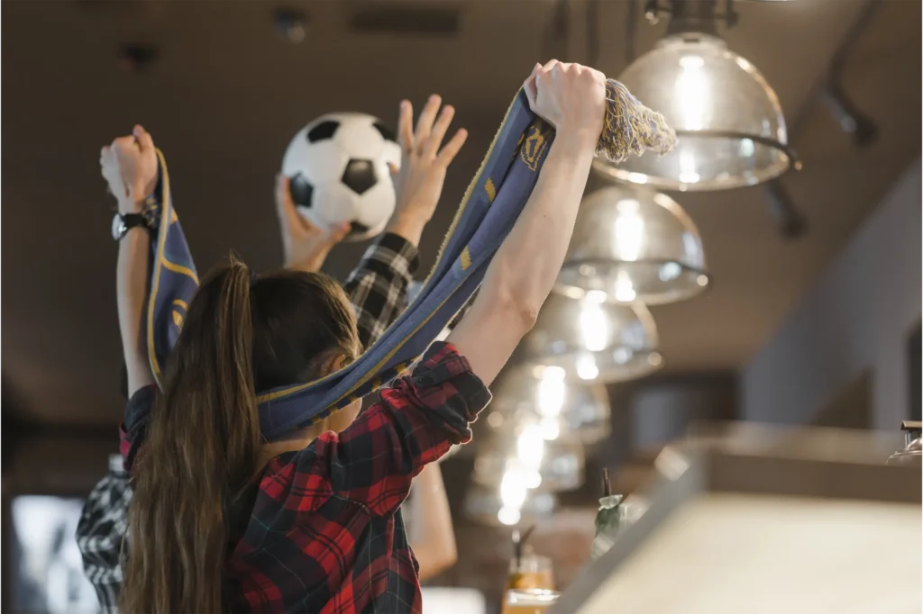 Aficionados celebrando con balon y bufanda en bar durante la Copa Mundo 2026 en Medellin.