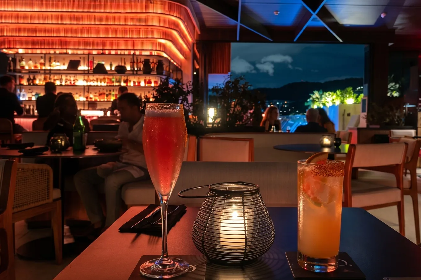 Cócteles de autor sobre mesa en Etro Rooftop de BINN Hotel con vista nocturna de Medellín al fondo