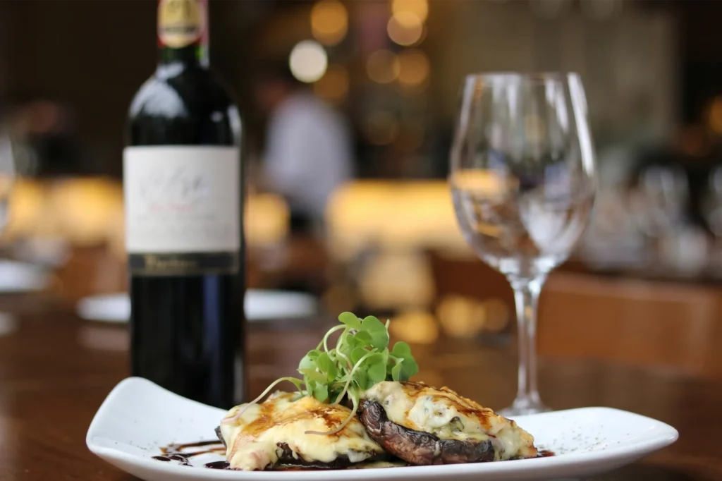 Portobello gratinado con queso y microgreens acompañado de vino tinto en Etro BINN Hotel