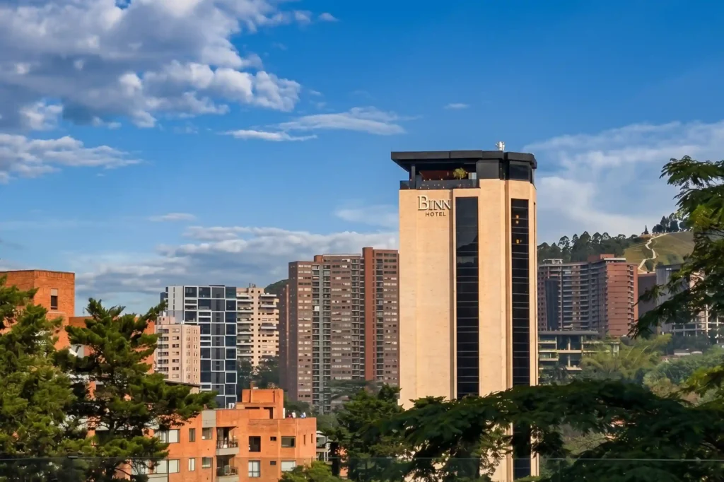 Torre de BINN Hotel destacada en el skyline de El Poblado con cielo azul y vegetacion