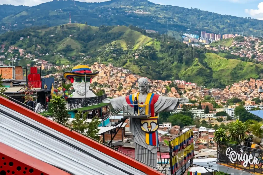 Medellín comunas viewpoint with colorful sculptures and panoramic view of the hillside neighborhoods.