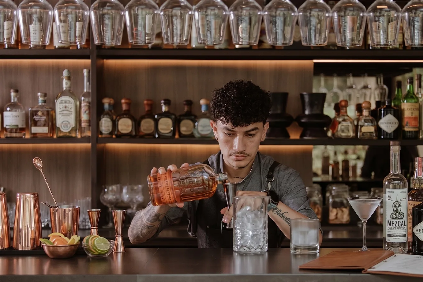 Bartender de Etro Rooftop en Binn Hotel vertiendo bourbon sobre hielo en la barra en Medellín.