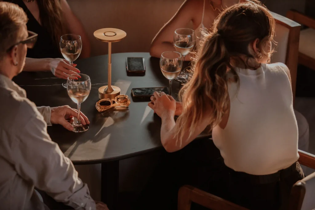 Grupo disfrutando vino en mesa de Etro Rooftop de Binn Hotel bajo luz cálida de tarde en Medellín.
