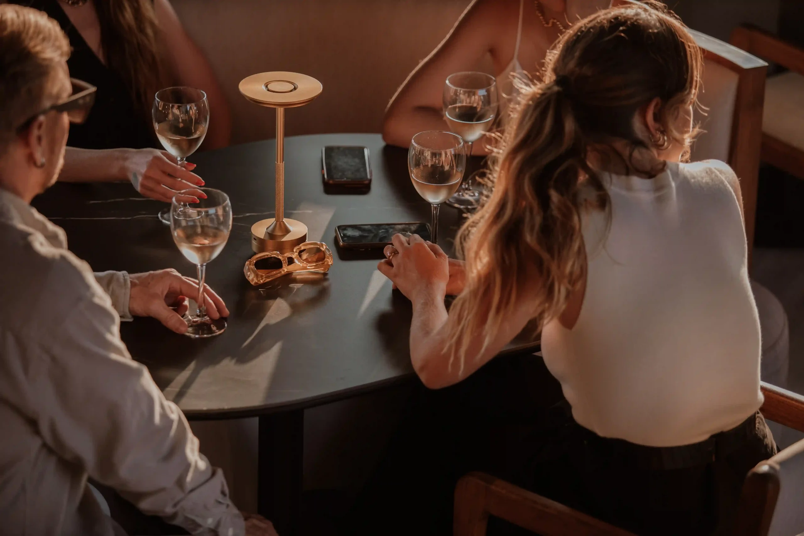 Grupo disfrutando vino en mesa de Etro Rooftop de Binn Hotel bajo luz cálida de tarde en Medellín.