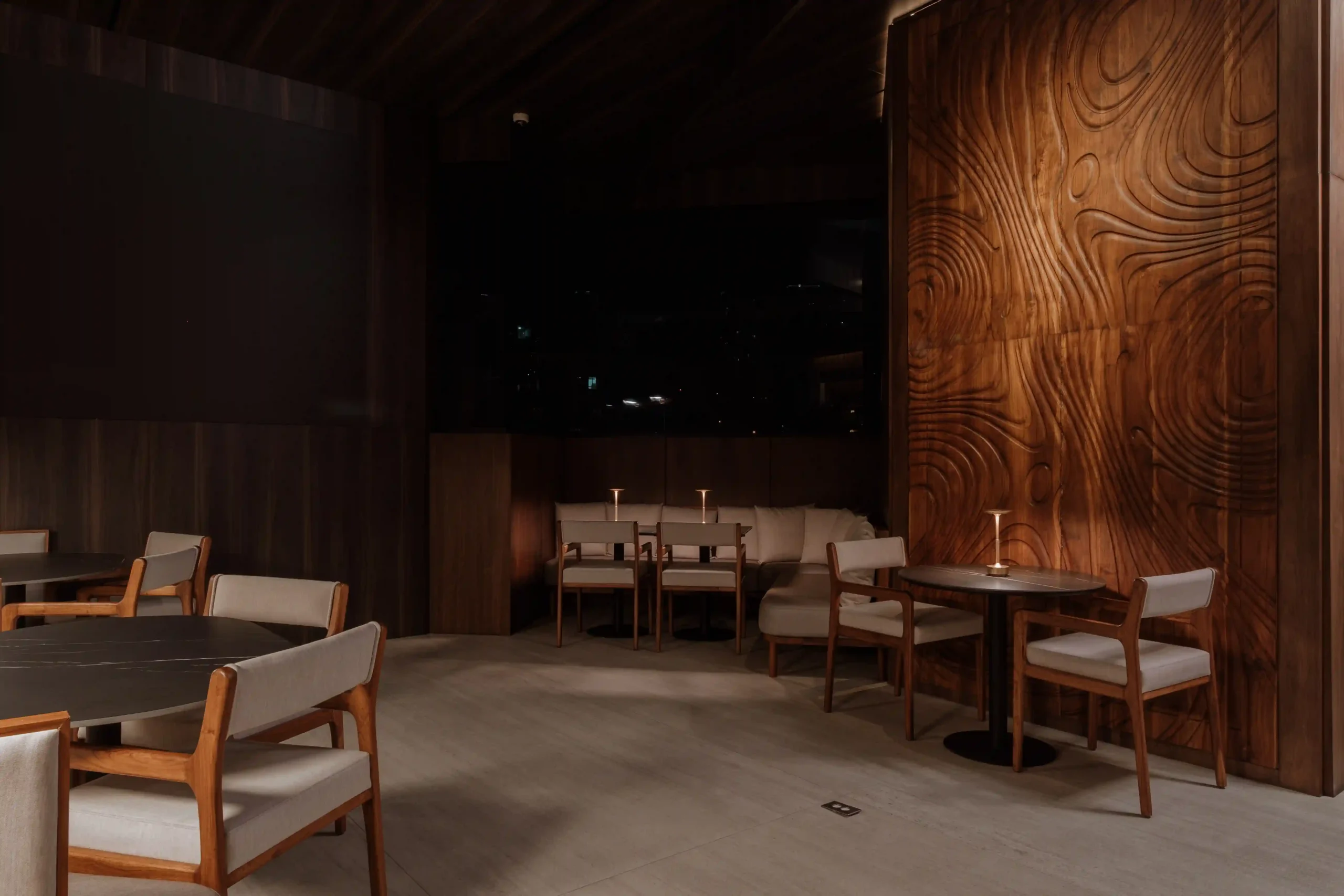 Salón interior de Etro Rooftop en Binn Hotel con panel de madera tallada y vista nocturna a Medellín