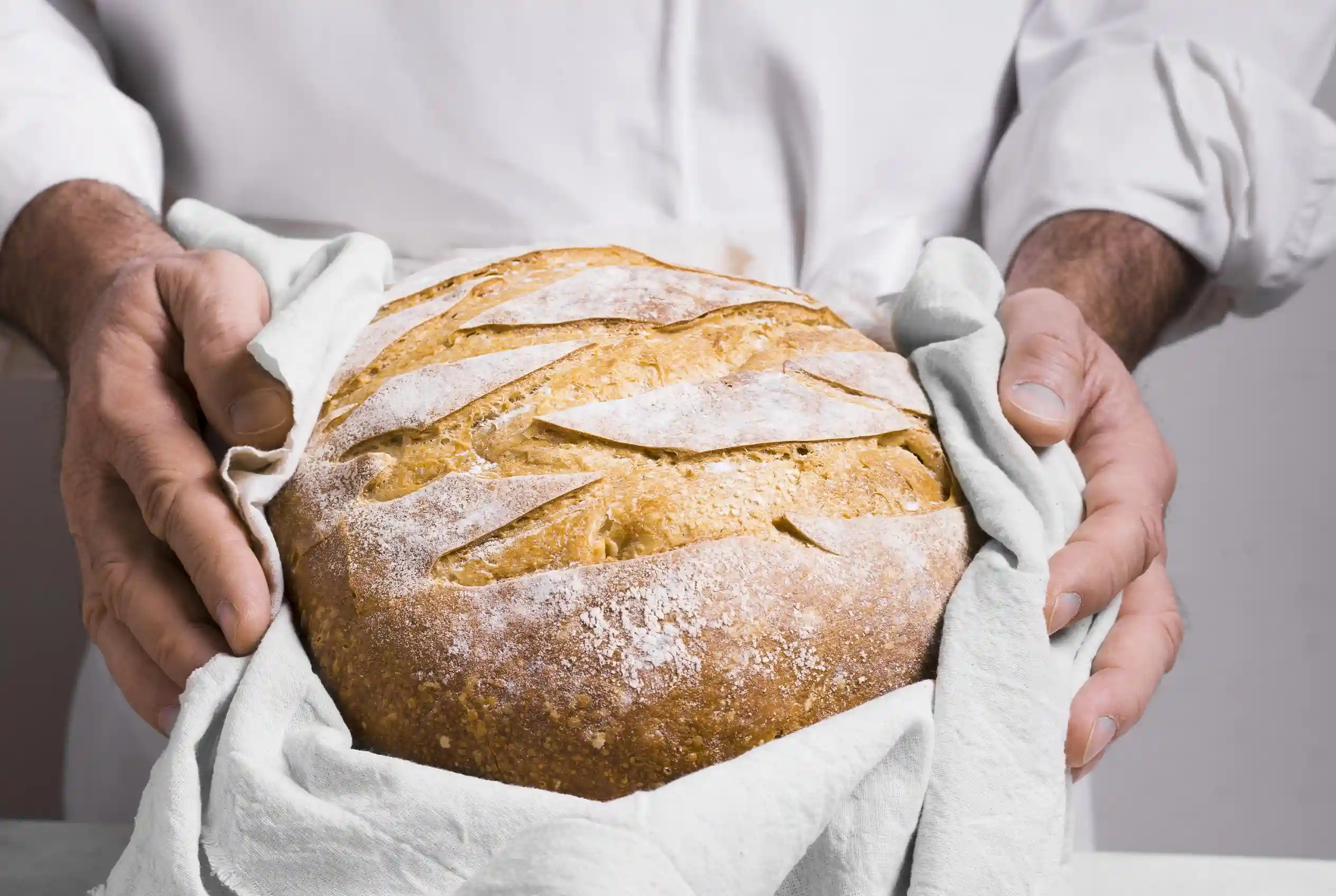 Chef sosteniendo hogaza de pan de masa madre con trigos ancestrales en La Makha, Medellín
