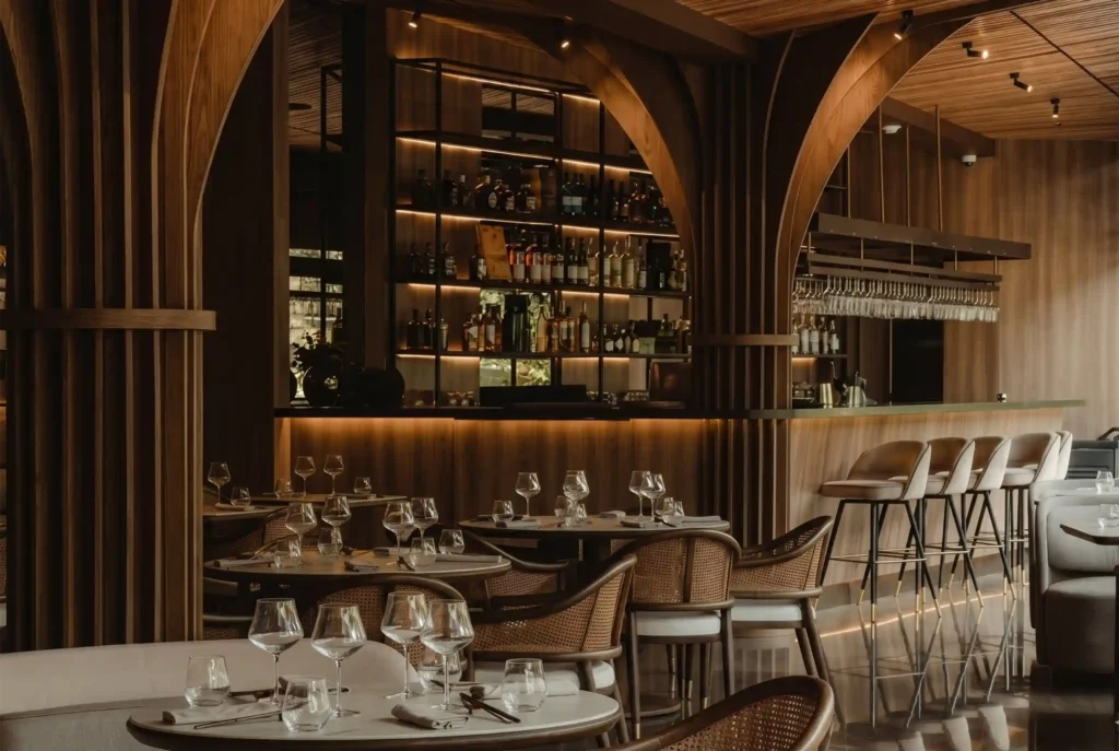 Salón y barra de La Makha con mesas, copas y estantería de licores en El Poblado, Medellín