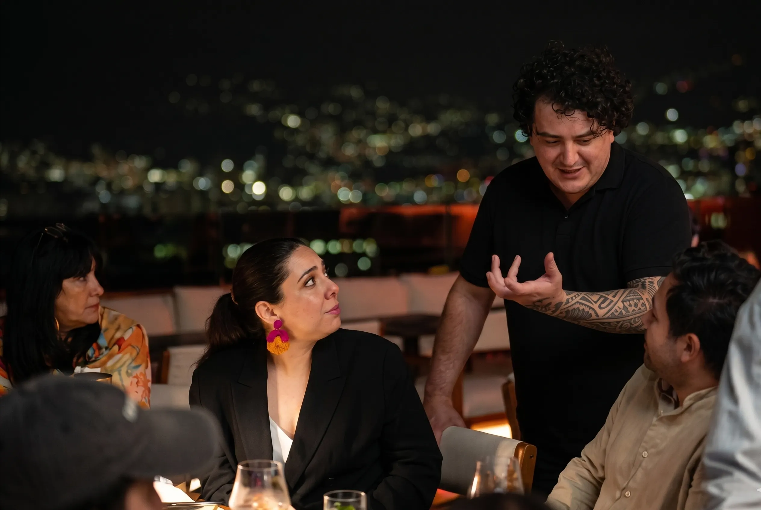 Chef David Suárez atendiendo comensales en terraza nocturna de La Makha con vista a Medellín