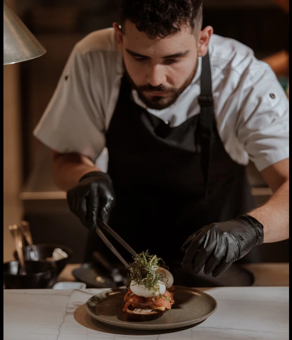 Chef precisely plating a gourmet toast at La Makha Restaurant in Binn Hotel Medellin.