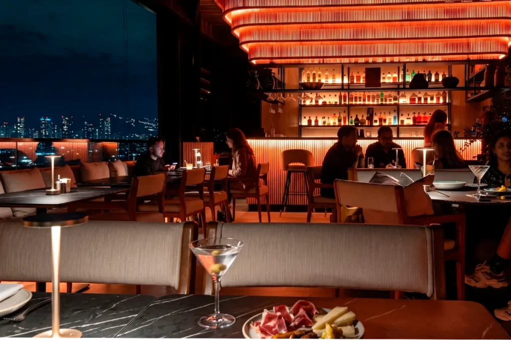 Martini and charcuterie board by Etro Rooftop's glowing bar on a Medellin night.