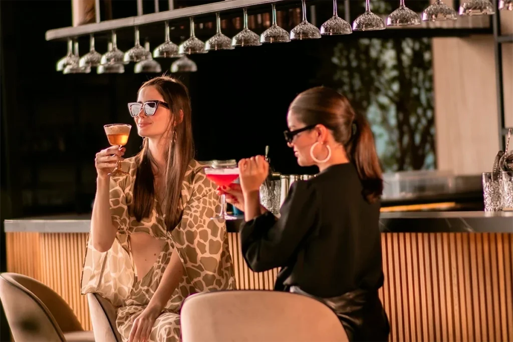 Friends toasting with signature cocktails by the bar at Etro Rooftop.