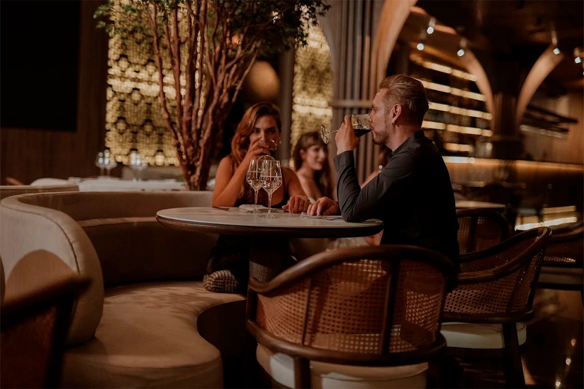 Guests enjoying a glass of wine at an intimate table inside Etro Rooftop.