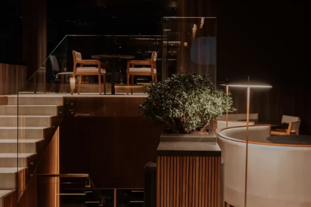 Wooden staircase and intimate corner at Etro Rooftop with a night view of Medellin.