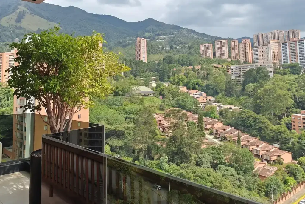 Balcony view featuring green trees and scenic mountain views of residential hillsides in Medellin