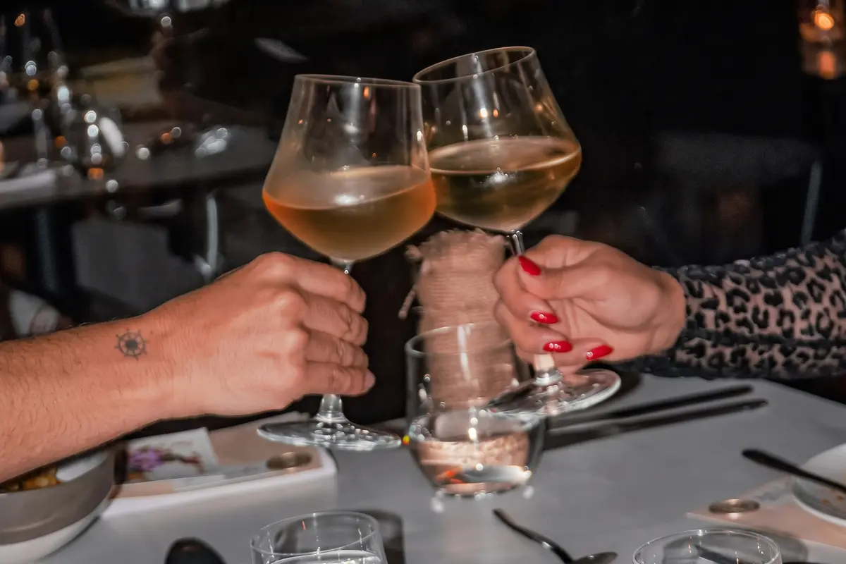 Couple toasting with wine glasses during a romantic anniversary dinner at Etro Rooftop Medellín.