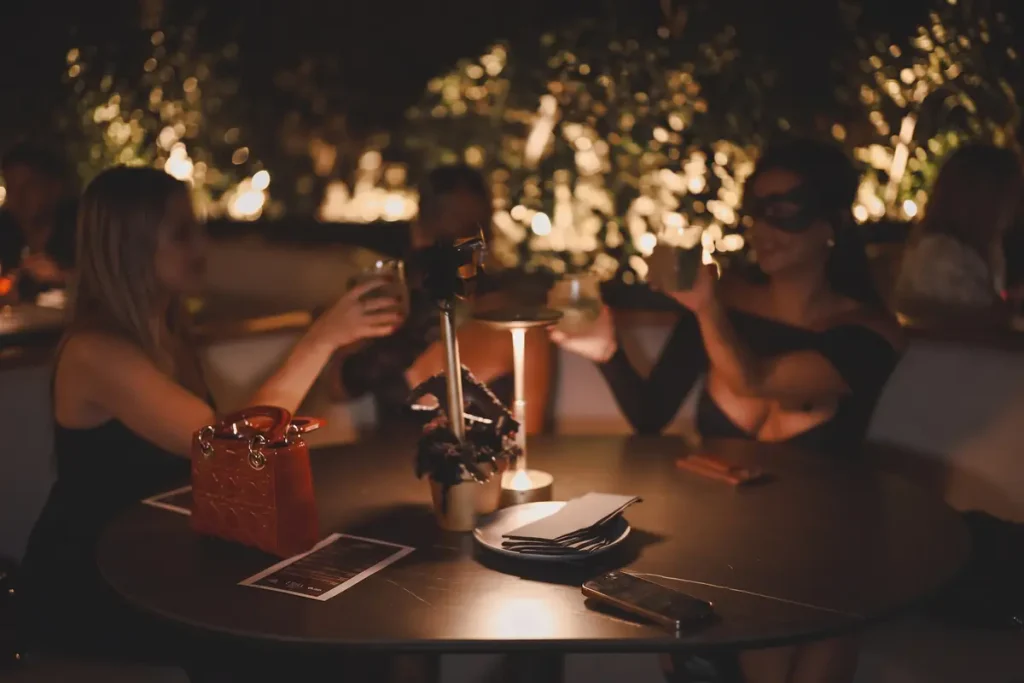 Mujeres brindando durante una fiesta temática de noche en una mesa iluminada de Etro Rooftop Medellín.