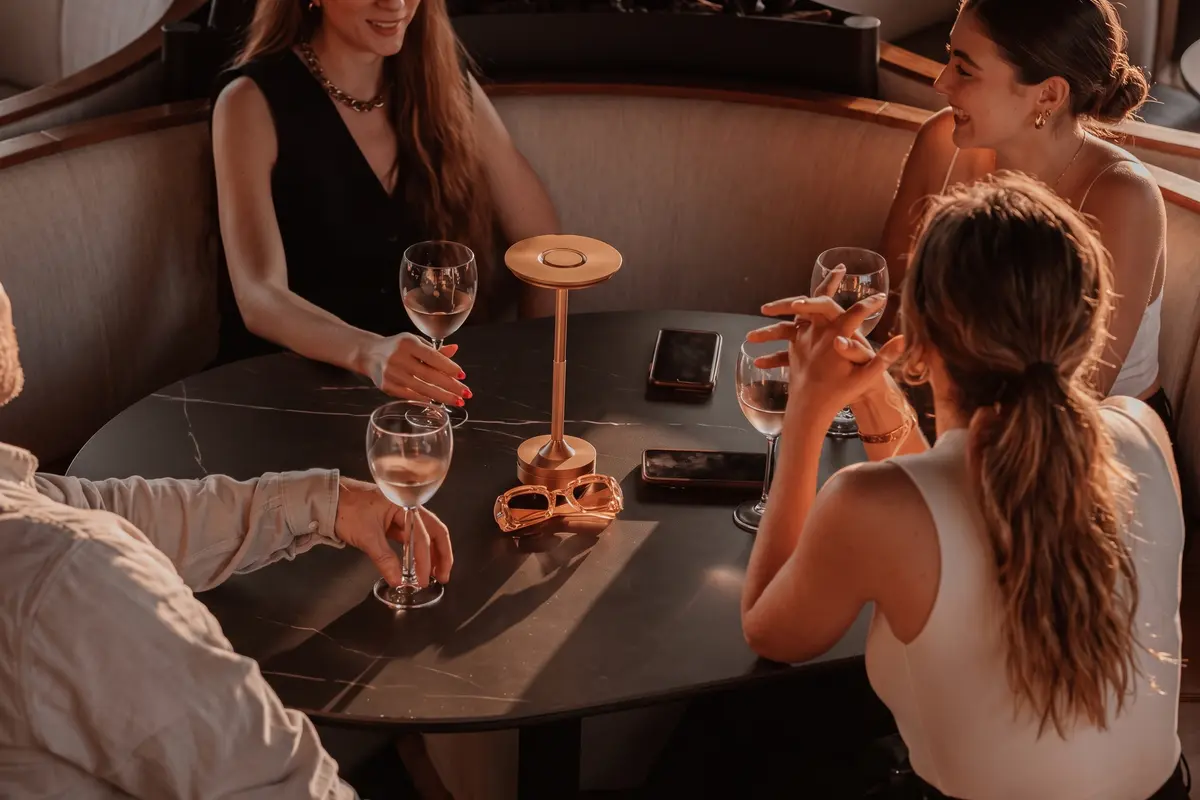 Group of friends enjoying drinks around a dimly lit table during golden hour at Etro Rooftop Medellín.