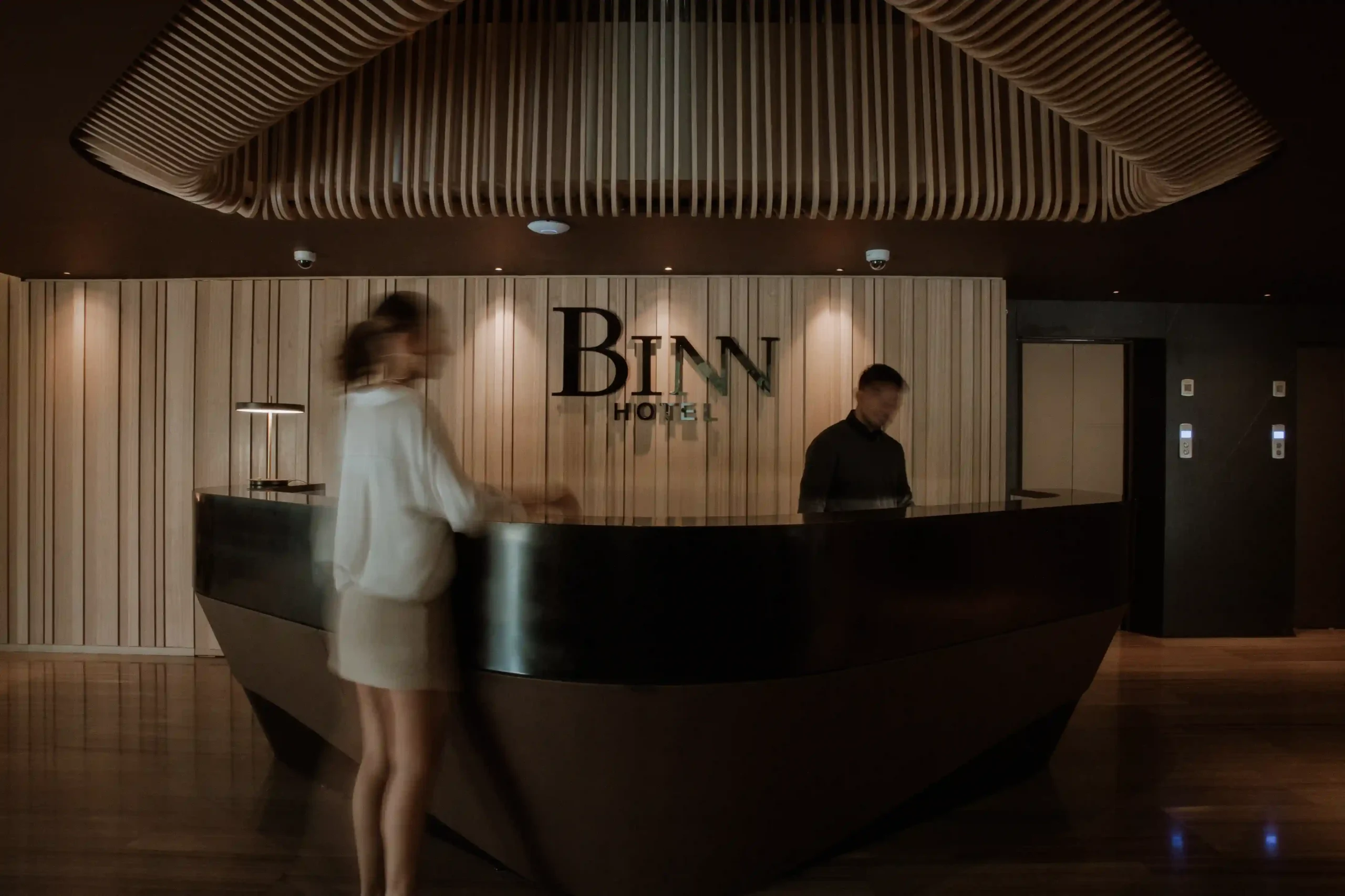 Front desk reception counter in the lobby of Binn Hotel Medellin with the logo on a wooden wall