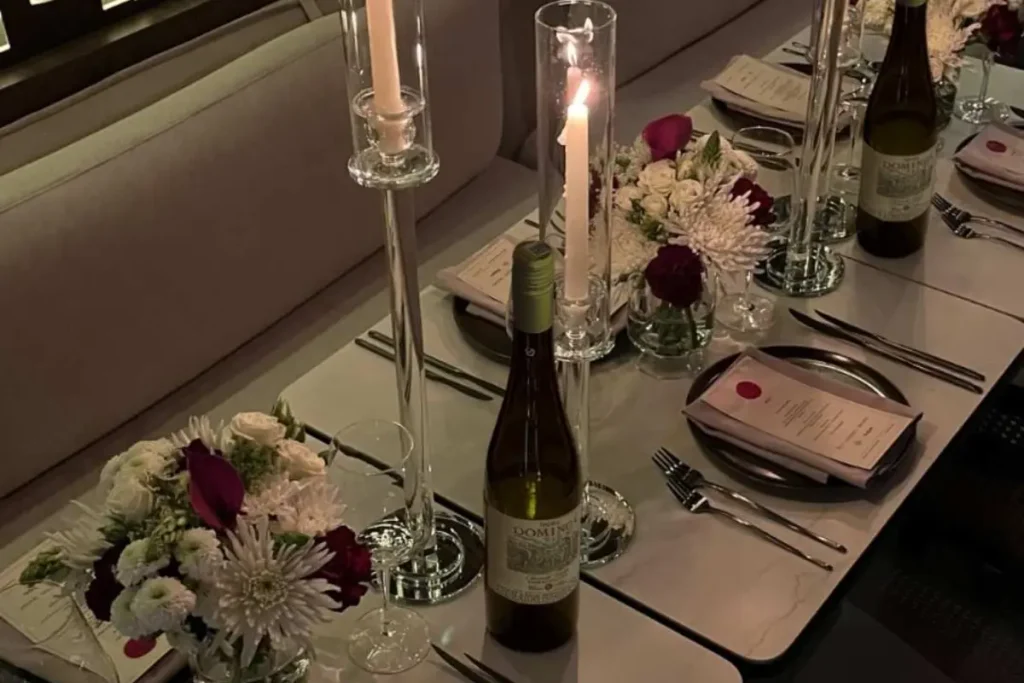 Elegant table set for a group dinner at La Makha with floral centerpieces, tall candles, wine bottles, and menus.