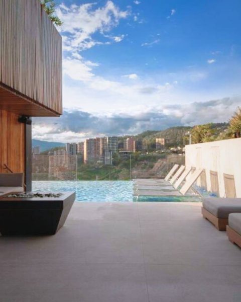 Área de descanso moderna junto a la piscina, con paredes de madera y vista a las montañas, ideal para brunch en Etro Rooftop