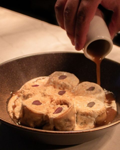 Persona vertiendo jarabe sobre un bol de helado, simbolizando la fusión de sabores en La Makha