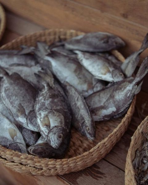Una cesta de pescado seco sobre una mesa de madera, mostrando un color marrón y textura arrugada, representando la pesca del día reinventada en La Makha.