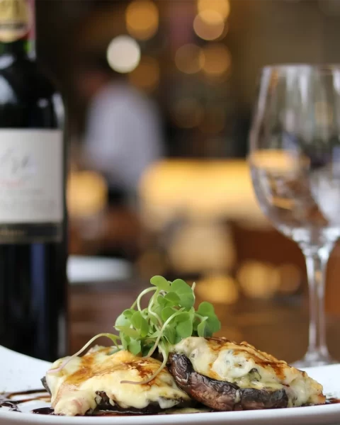Portobello gratinado con queso y microgreens acompañado de vino tinto en Etro BINN Hotel