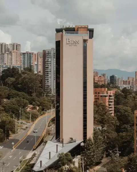 Fachada completa de BINN Hotel en El Poblado rodeada del skyline de Medellín y cordillera.