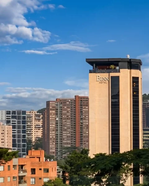 Torre de BINN Hotel destacada en el skyline de El Poblado con cielo azul y vegetacion