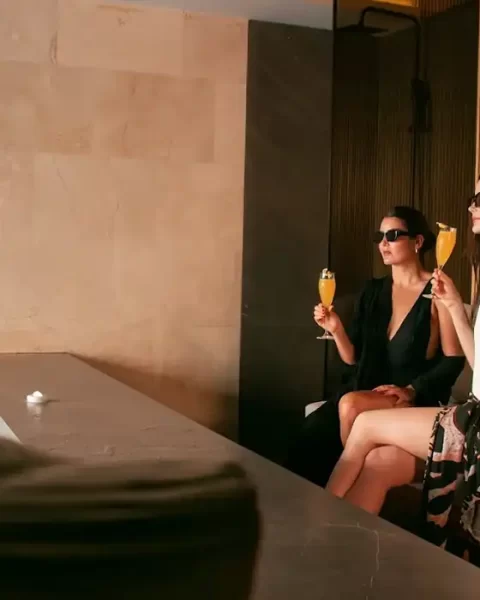 Dos mujeres con cócteles en área de spa y piscina interior de BINN Hotel, plan madre e hija en Medellín.