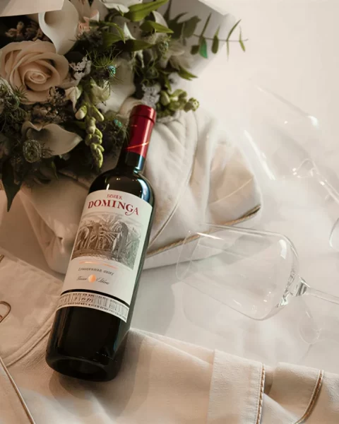 Botella de vino, flores y copas sobre bata de baño en habitación de BINN Hotel.