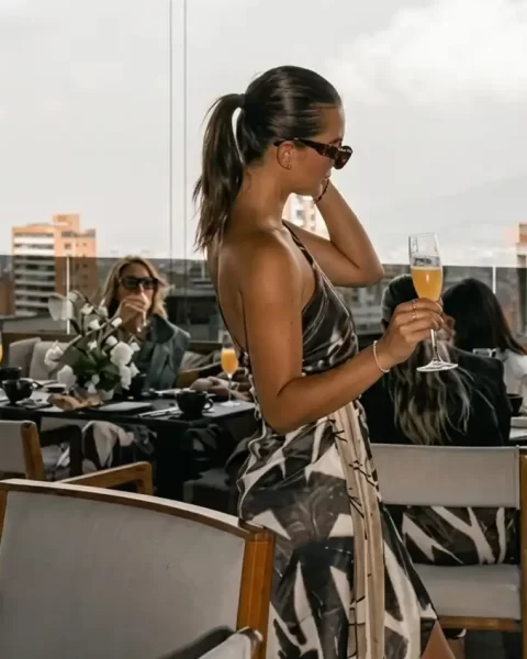 Mujer con copa de champaña en terraza de Etro Rooftop Medellín; ambiente de celebración por el Día de la Madre.