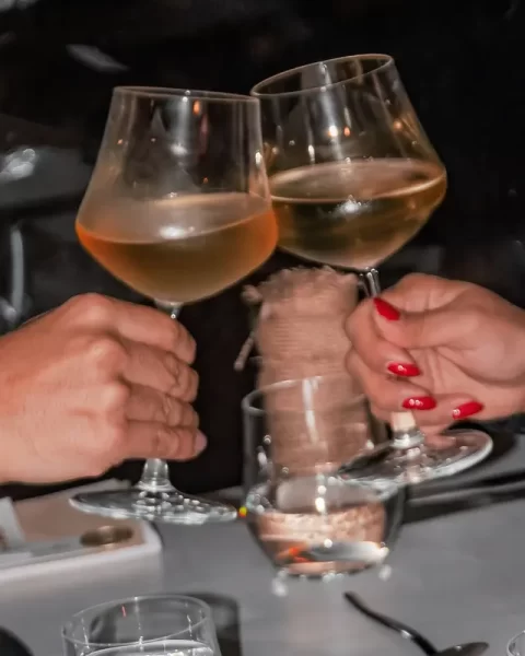 Pareja haciendo un brindis con copas de vino durante una cena de aniversario en Etro Rooftop Medellín.