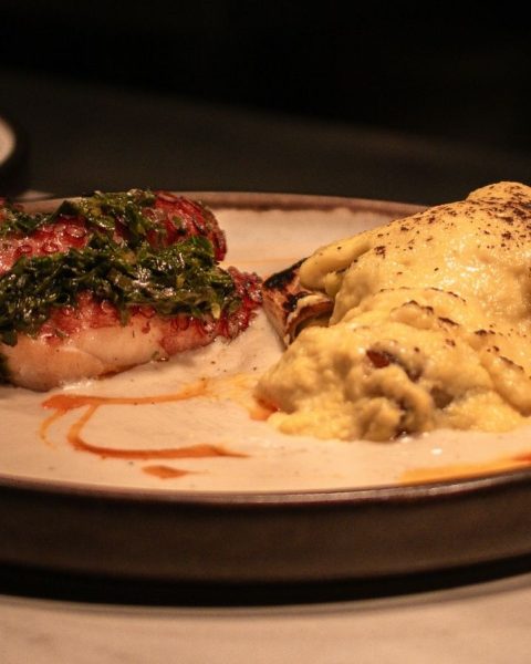 Un plato con comida colorida sobre una mesa, representando la cocina de raíz