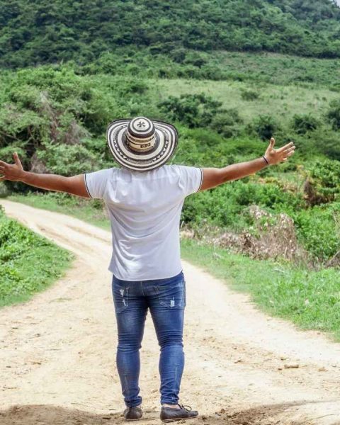 Hombre de pie en un origen camino de tierra, con los brazos abiertos, expresando alegría y conexión tecnica con el entorno