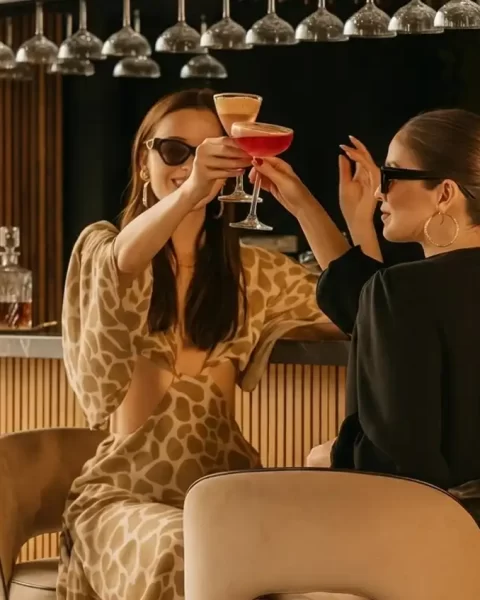 Brindis del Día de la Madre en Etro Rooftop Medellín: dos mujeres con cócteles de autor en una barra de lujo moderna.