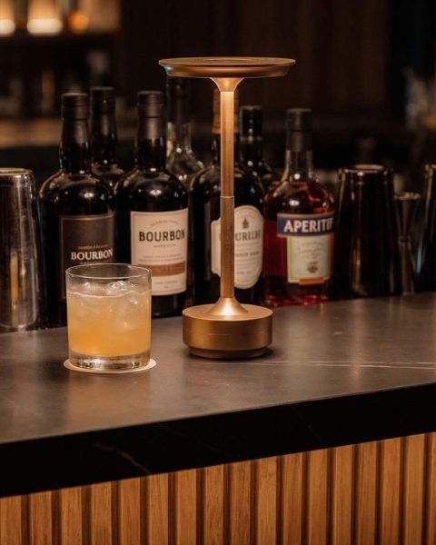 Cóctel artesanal con ingredientes locales servido en rooftop de Medellín con barra elegante y selección de licores premium de fondo