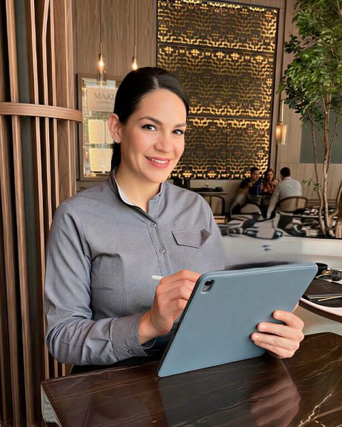 Personal del restaurante La Makha en Medellín gestionando una reserva en una tablet desde el elegante salón principal.