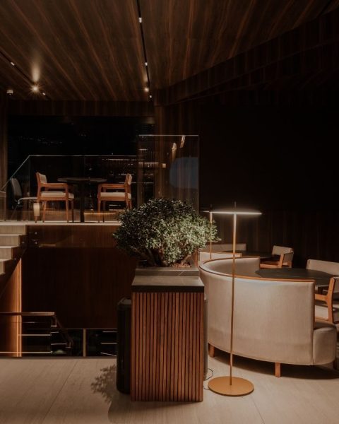 Arquitectura interior de dos niveles en Etro Rooftop de Binn Hotel con escalera de madera y sillones de noche.
