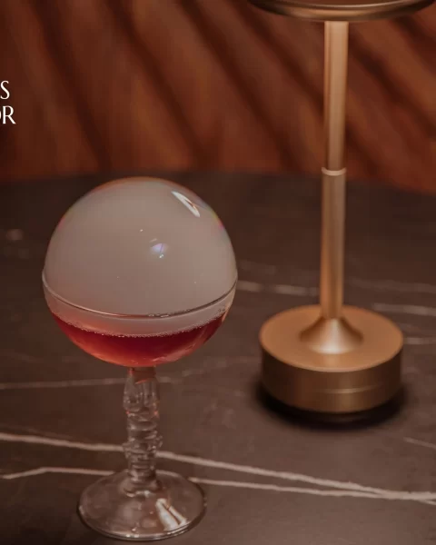 Cóctel de autor con esfera de hielo ahumada en copa de cristal sobre mesa de mármol en ETRO Rooftop, BINN Hotel Medellín