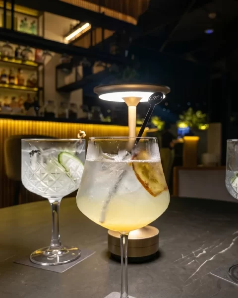 Tres cócteles en copas de cristal sobre mesa de mármol en Etro Rooftop de Binn Hotel