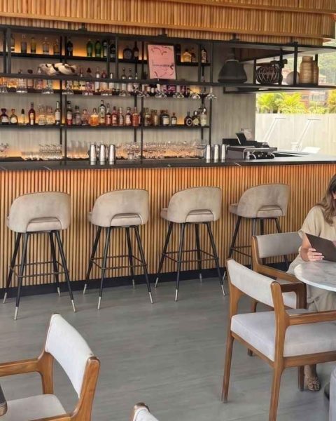 Madre e hija sonriendo mientras ven el menú en Etro Rooftop Medellín, con barra de madera moderna y vista a la ciudad.