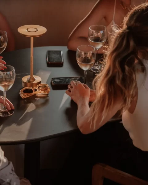 Grupo disfrutando vino en mesa de Etro Rooftop de Binn Hotel bajo luz cálida de tarde en Medellín.